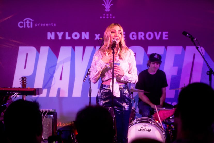 Katelyn Tarver on a stage singing into a microphone facing the crowd