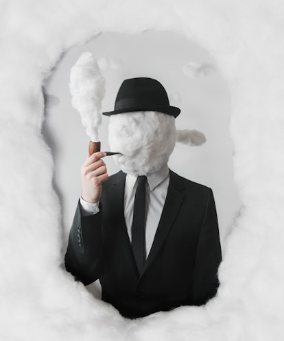 A man posing in a suit whose head is made of smoke