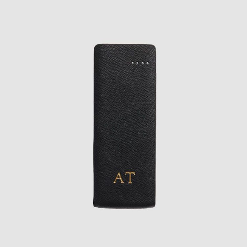 The Daily Edited's Monogrammed Black Phone Charger with "A.T." engraved on it in gold 