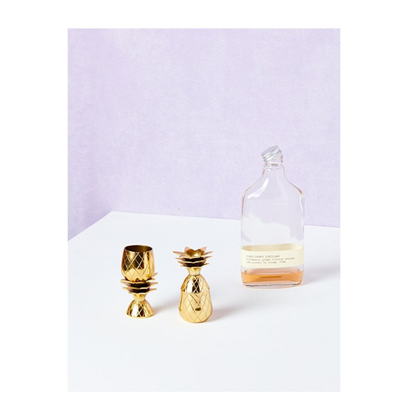 W&P, golden Pineapple Shot Glasses (set of two) with a bottle of alcohol next to them