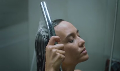 A young black haired woman washing her hair in the shower