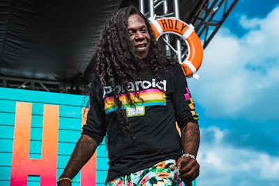 Big Freedia while performing in a black long-sleeved shirt with a polaroid center part print a flora...