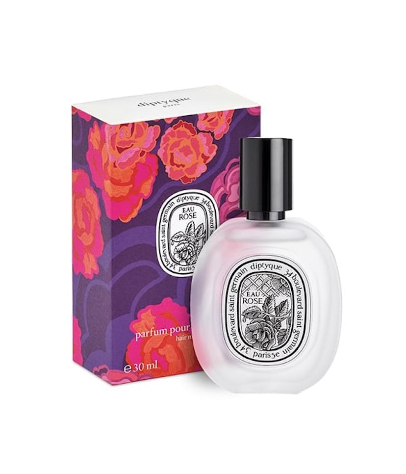 A bottle of Diptyque's Eau Rose Hair Mist placed in front of its floral packaging 