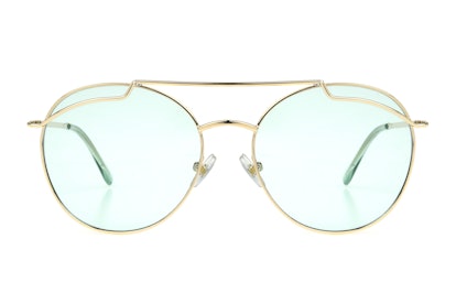 A pair of sunglasses with a golden frame and an oval shape, from Kat Graham's collection, called "Th...