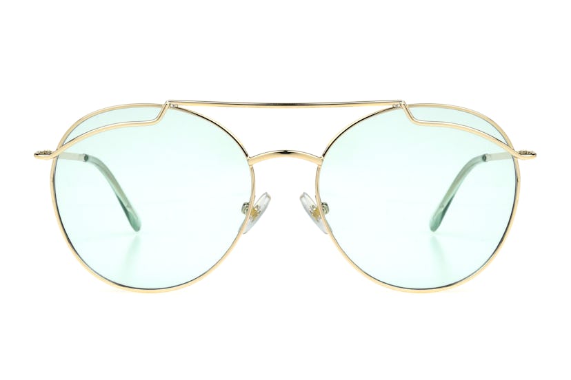 A pair of sunglasses with a golden frame and an oval shape, from Kat Graham's collection, called "Th...