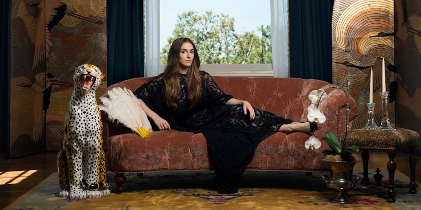 Annamarie Tendler Mulaney posing on a couch while wearing a long black dress