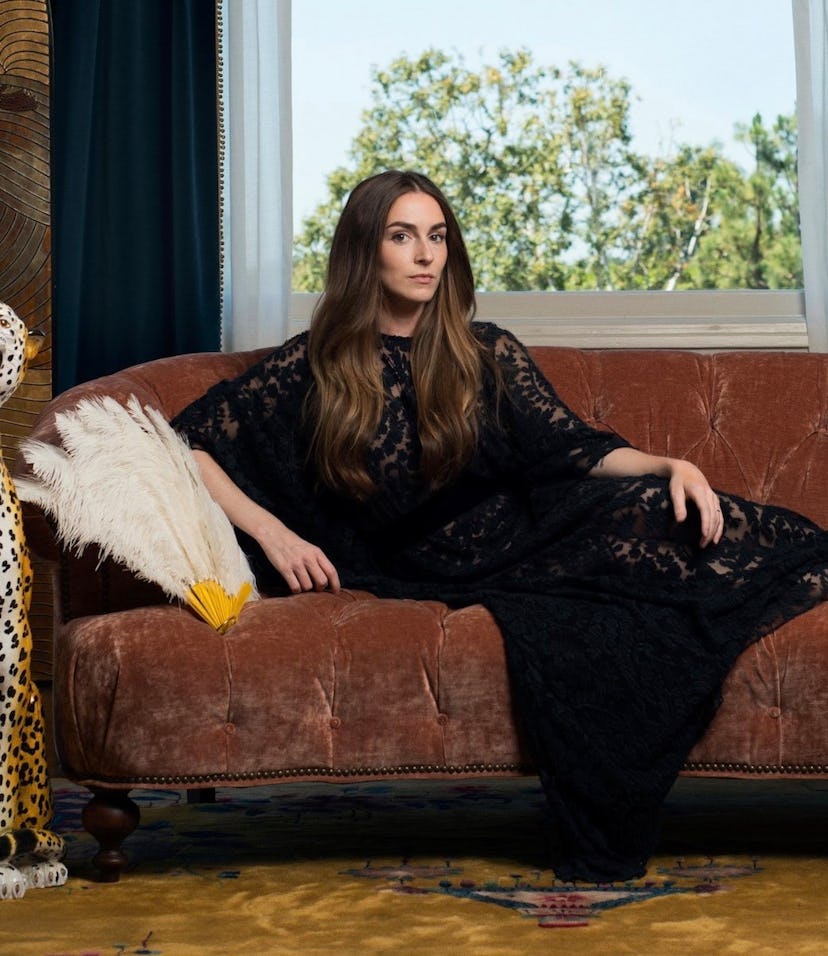 Annamarie Tendler Mulaney posing on a couch while wearing a long black dress