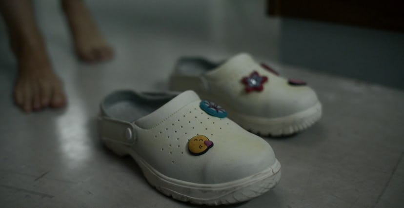 White Crocs decorated with cute stickers of emojis and flowers