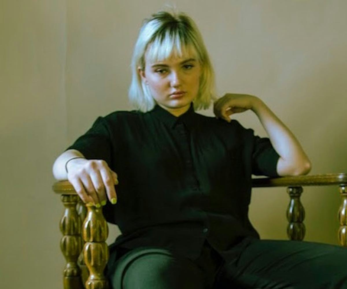 Jackie Carlson, star of 'Family Reunion,' in a black shirt and green pants, sitting on an antique ch...