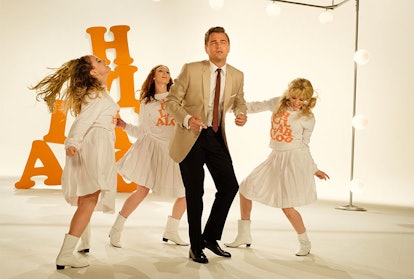 Leonardo DiCaprio wearing a beige jacket while dancing with three ladies dressed in white dresses
