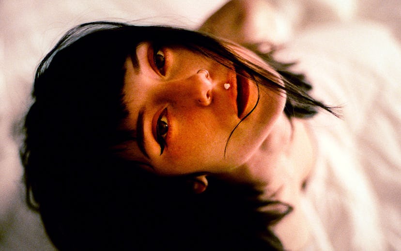 The musician Kitty with a black bob haircut looking up with two nose piercings on both sides and an ...