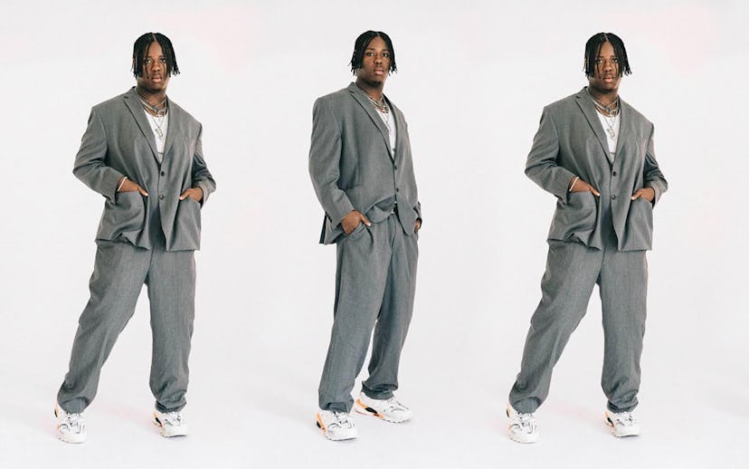 Denzel Dion posing in a classic gray oversized suit