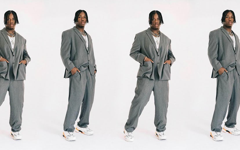 Denzel Dion posing in a classic gray oversized suit  