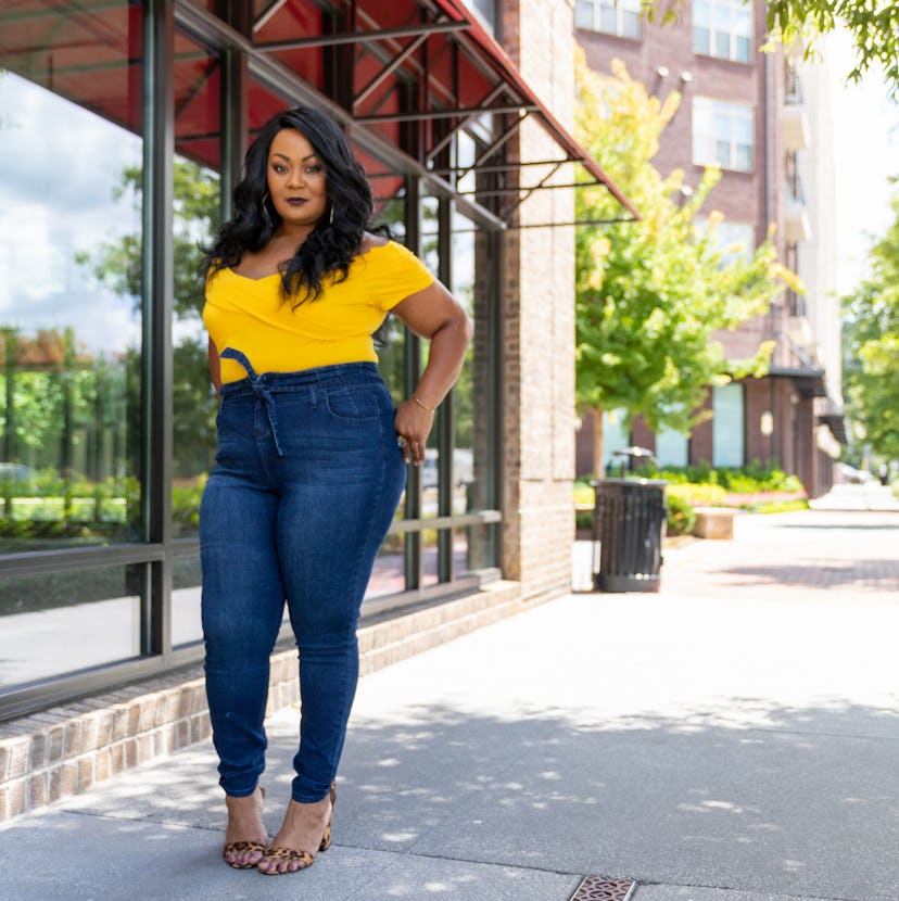 Founder of The Curvy Fashionista, Marie Denee wearing a yellow shirt and jeans