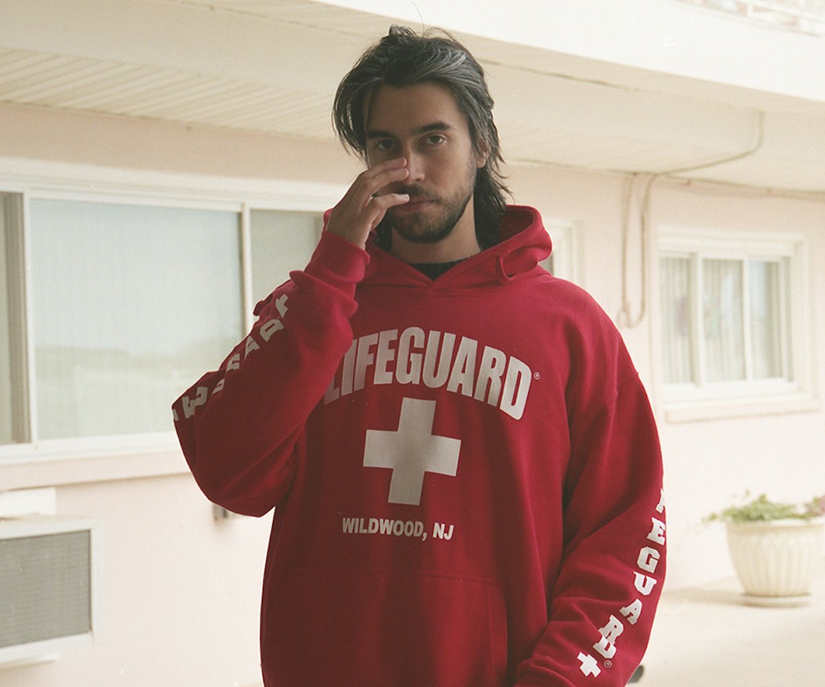 Long-haired Alex G wearing a red hoodie with "lifeguard" text on it