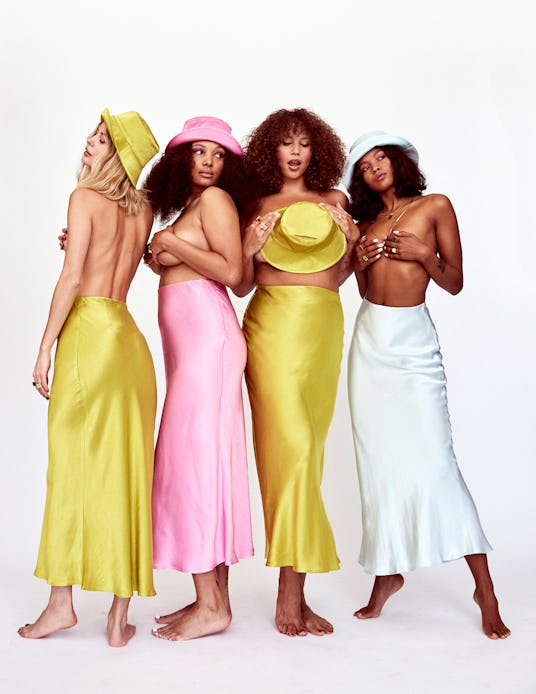 Topless models in long yellow, pink, and white satin skirts with matching hats