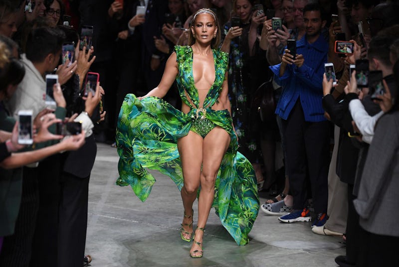 Jennifer Lopez walking down the catwalk in a sleeveless green Versace gown with a palm tree print an...