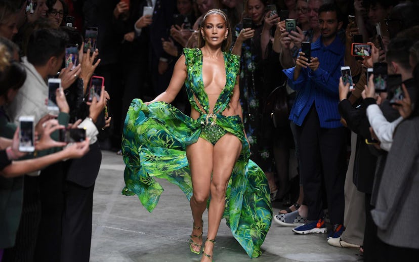 Jennifer Lopez walking down the catwalk in a sleeveless green Versace gown with a palm tree print an...