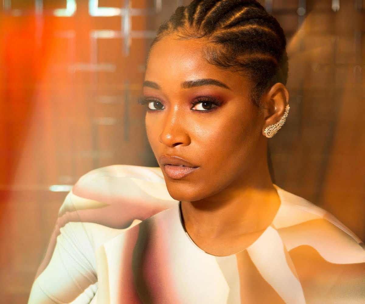 Keke Palmer  with tightly braided hair and in a pink shirt looking at the camera