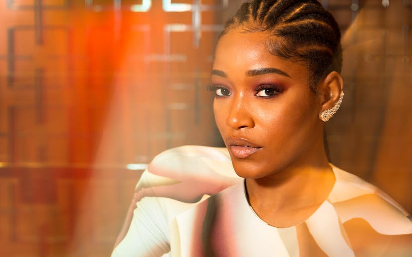 Keke Palmer with tightly braided hair and in a pink shirt looking at the camera