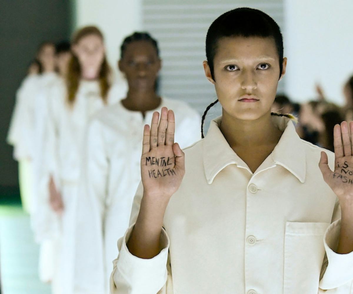 Gucci model walking a runway while wearing all blue and holding her hand up with text "Mental health...