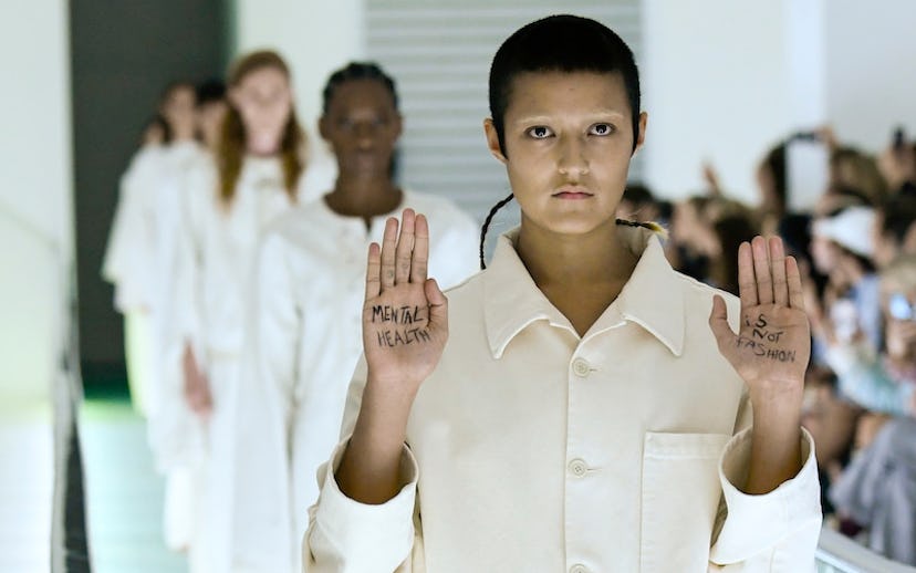 Gucci model walking a runway while wearing all blue and holding her hand up with text "Mental health...