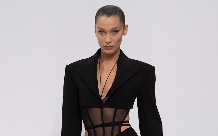 Bella Hadid with minimal make-up, ponytail and a sheer corset and lined tights under her suit