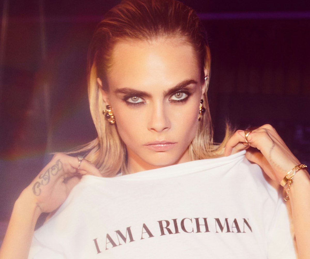 English model Cara Delevingne in inspired holiday collection for Nast Gal holding a white T-shirt wi...