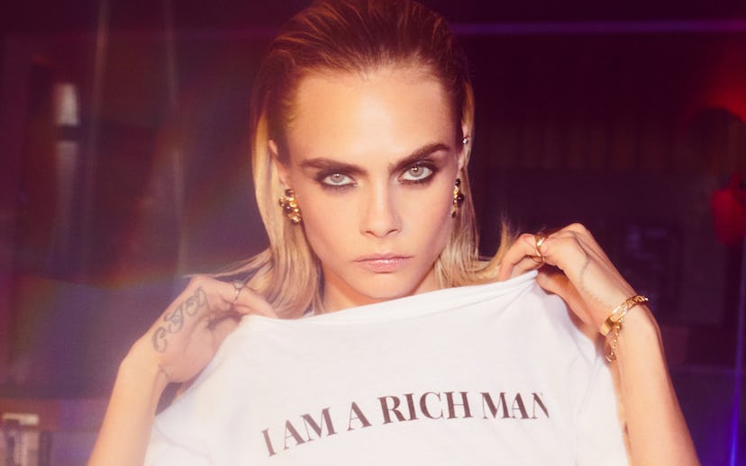English model Cara Delevingne in inspired holiday collection for Nast Gal holding a white T-shirt wi...