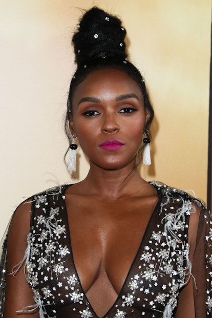 Janelle Monáe posing in a black dress with her hair in a bedazzled bun 