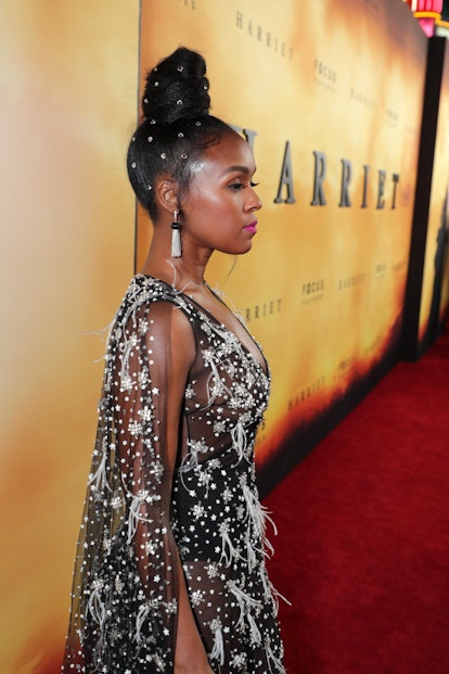 Janelle Monáe posing in a black bedazzled dress with a bedazzled bun hairstyle 