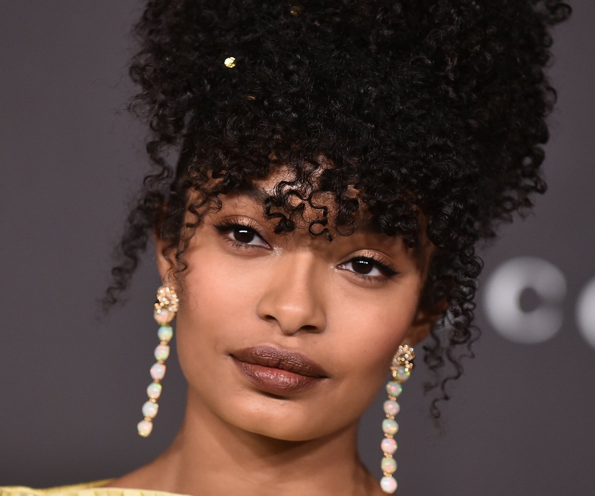 Yara Shahidi at the LACMA Gala with an up-do curly hairstyle and long gem earrings