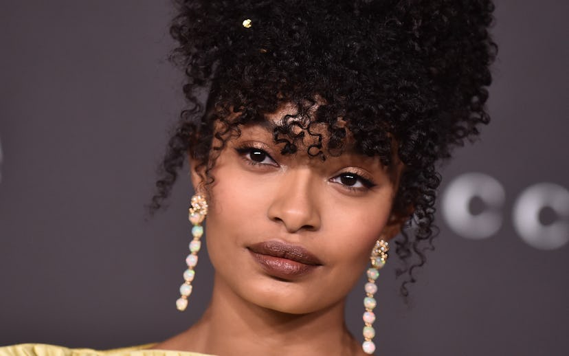 Yara Shahidi at the LACMA Gala with an up-do curly hairstyle and long gem earrings