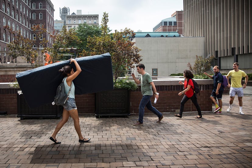 People carrying mattresses down a street