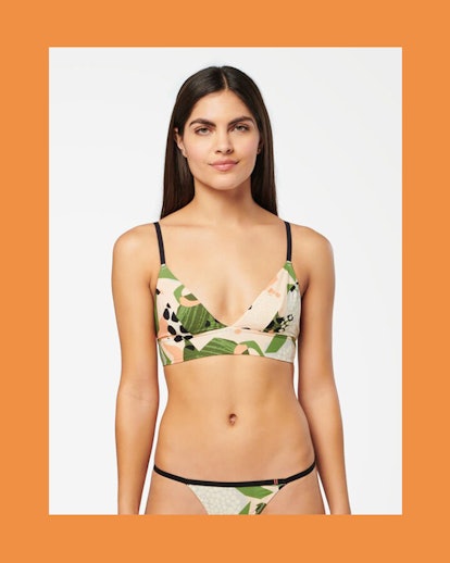 The model dressed in a triangle crop and string thong in a tropical print by Stance.