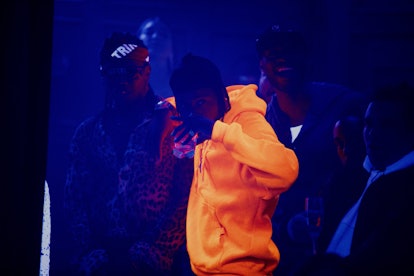 LaKeith Stanfield wearing a neon orange jumper in the club in "Uncut Gems"