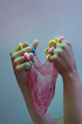 Hands with all different kinds of childlike rings of different colors such as green, yellow, pink