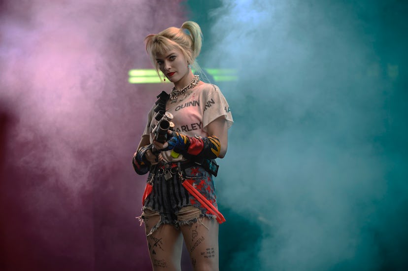 Margot Robbie as Harley Quinn in the "Birds of Prey" movie holds a gun with smoke behind her