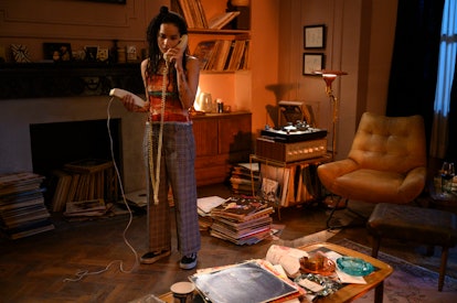 Zoe Kravitz in a cluttered living room in High Fidelity wearing a multicolored striped shirt, checke...