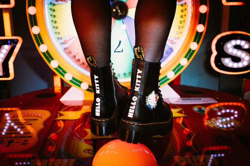 A person wearing black Dr. Martens Jadon Hello Kitty Boots with a roulette wheel behind