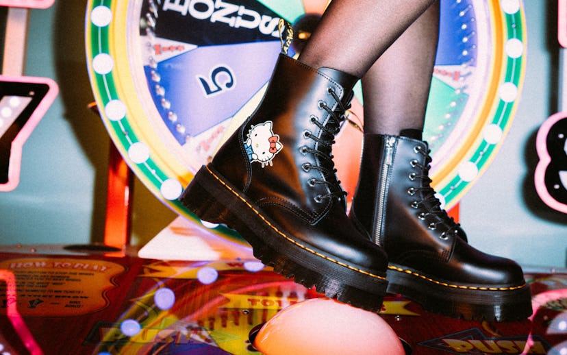 A person wearing black Dr. Martens Jadon Hello Kitty Boots with a roulette wheel behind