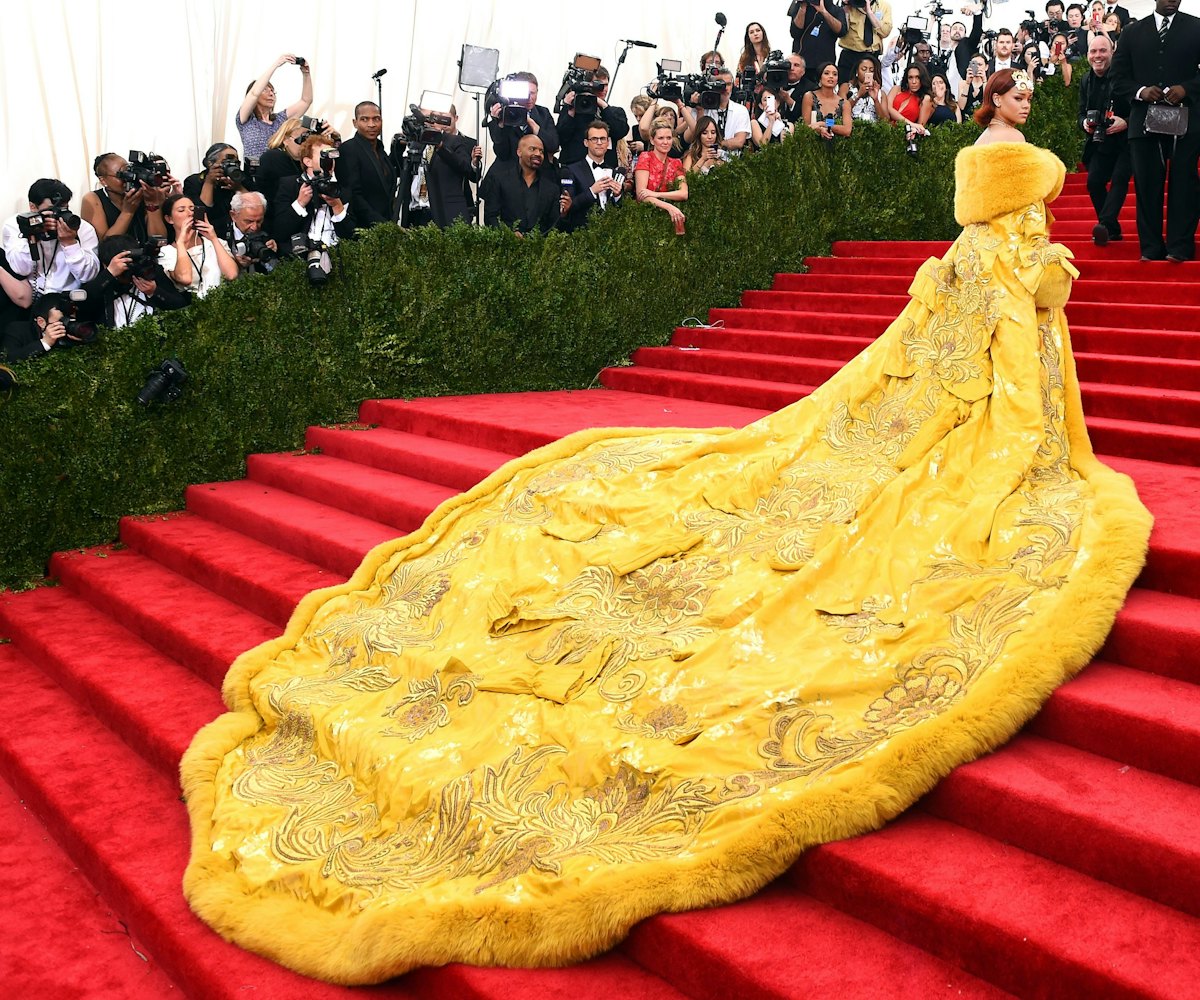 Rihana in a long yellow dress going up the stairs at the MET gala