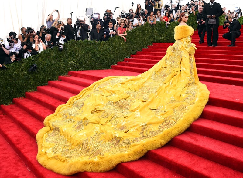 Rihana in a long yellow dress going up the stairs at the MET gala