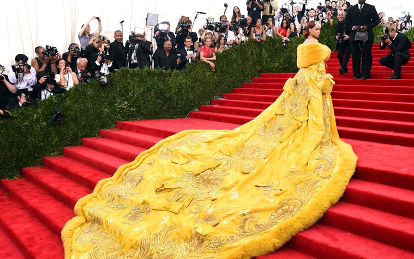 Rihana in a long yellow dress going up the stairs at the MET gala