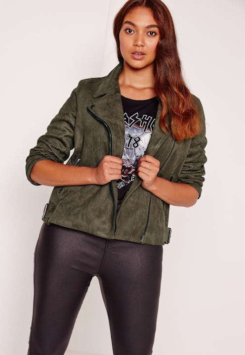A model with long red hair, wearing black leather pants and a black printed t-shirt with olive-green...