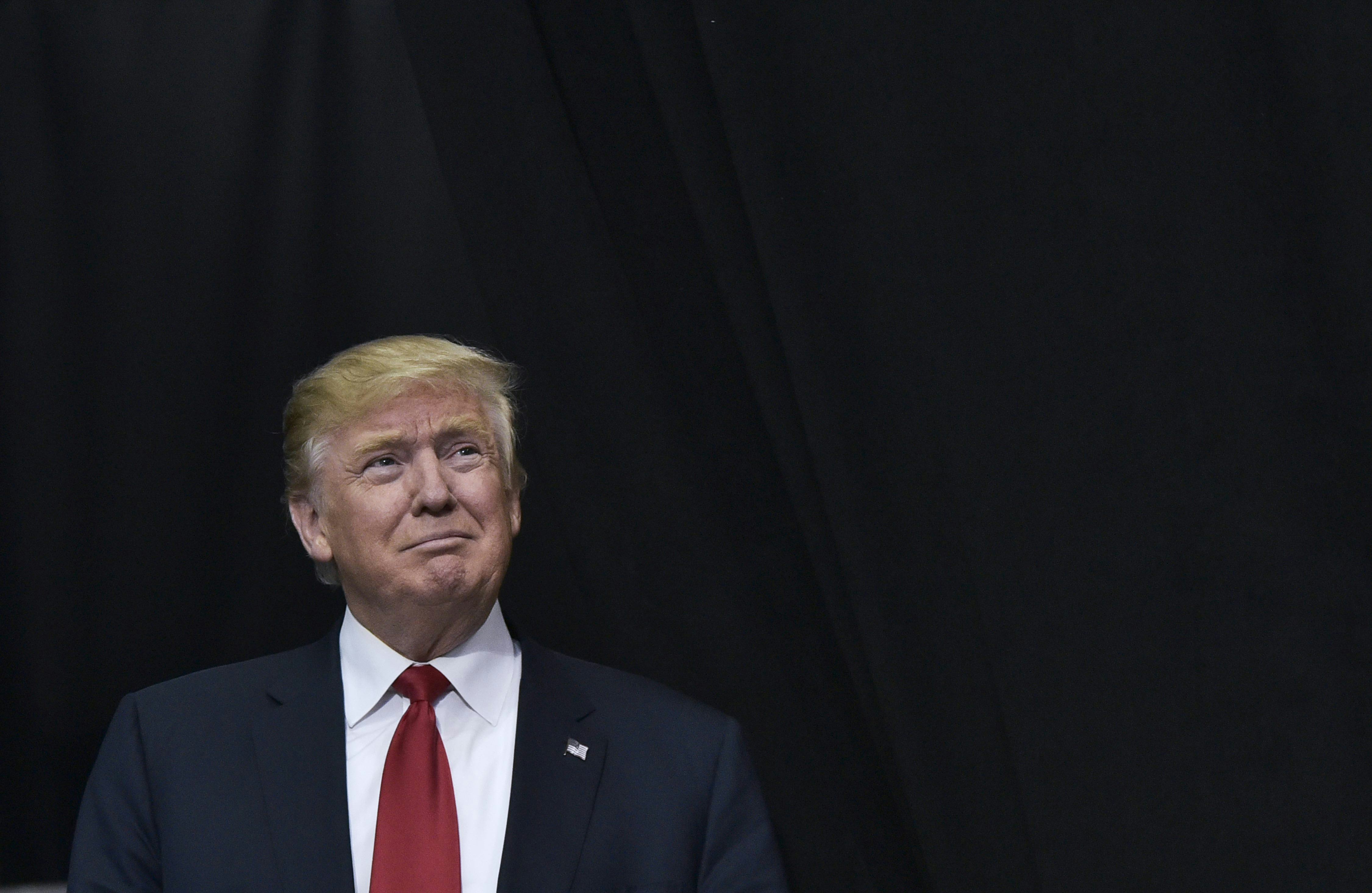 Donald Trump wearing a suit in front of a black background