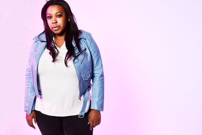 A grown-ass woman posing in a white shirt and light blue jacket