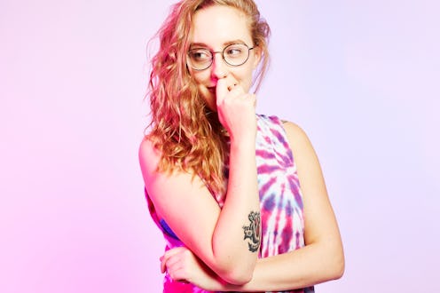 Young blonde girl in a thinking pose with an index finger on her mouth and right elbow on left fist