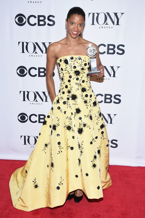 Renee Elise Goldsberry wearing a strapless yellow gown with black details while holding the Tony awa...