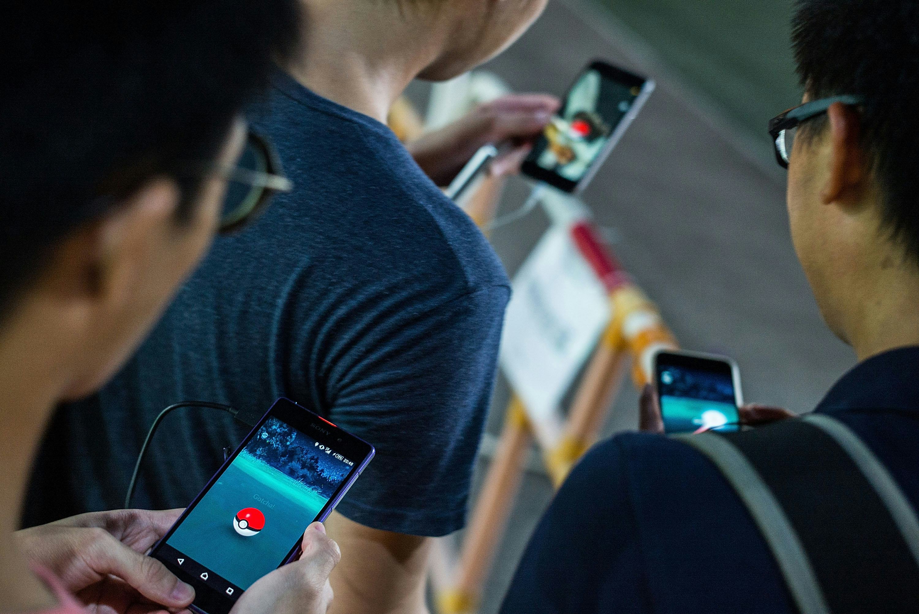Three friends playing Pokemon Go on their smartphones